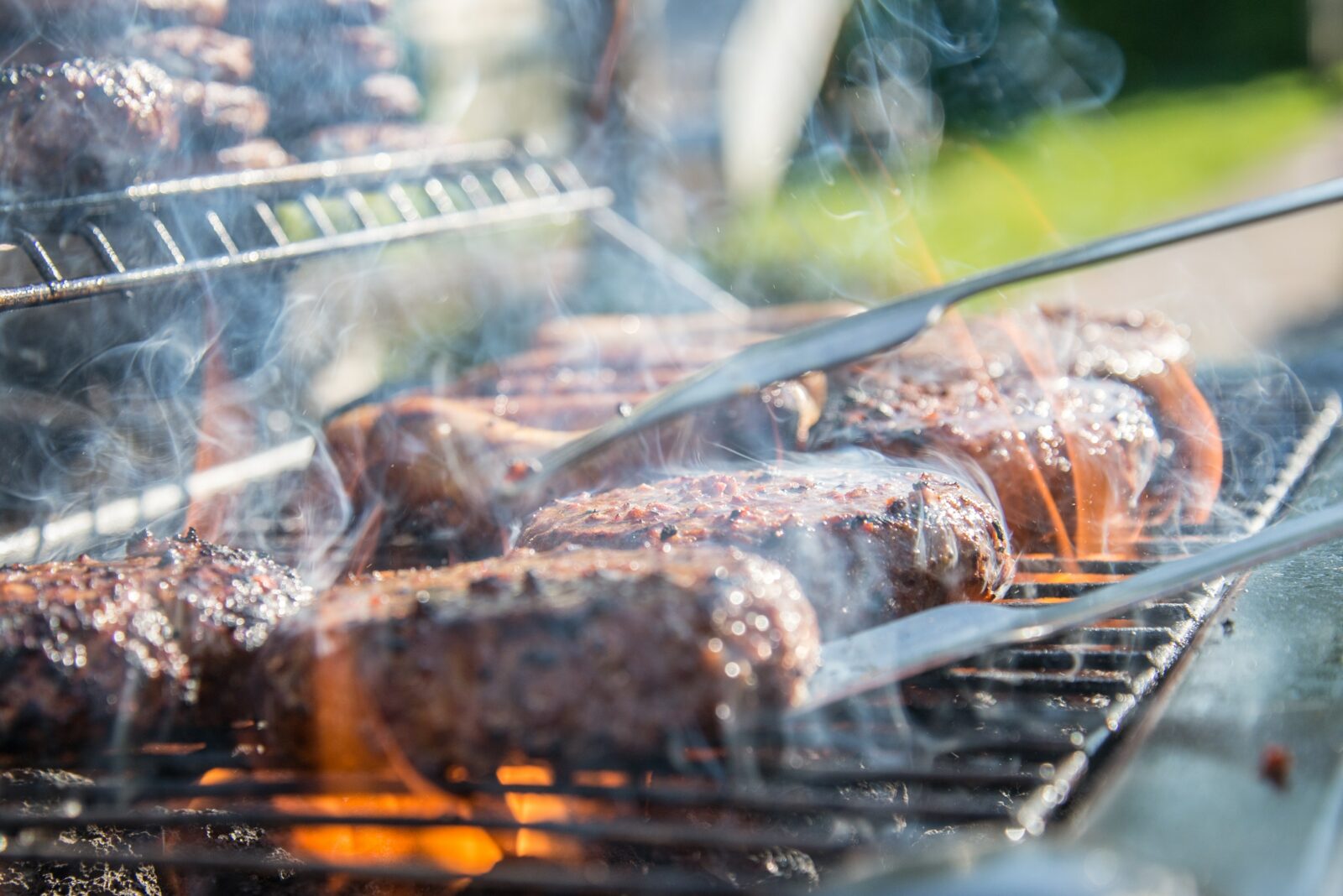 picture of person bbqing meat with tongs