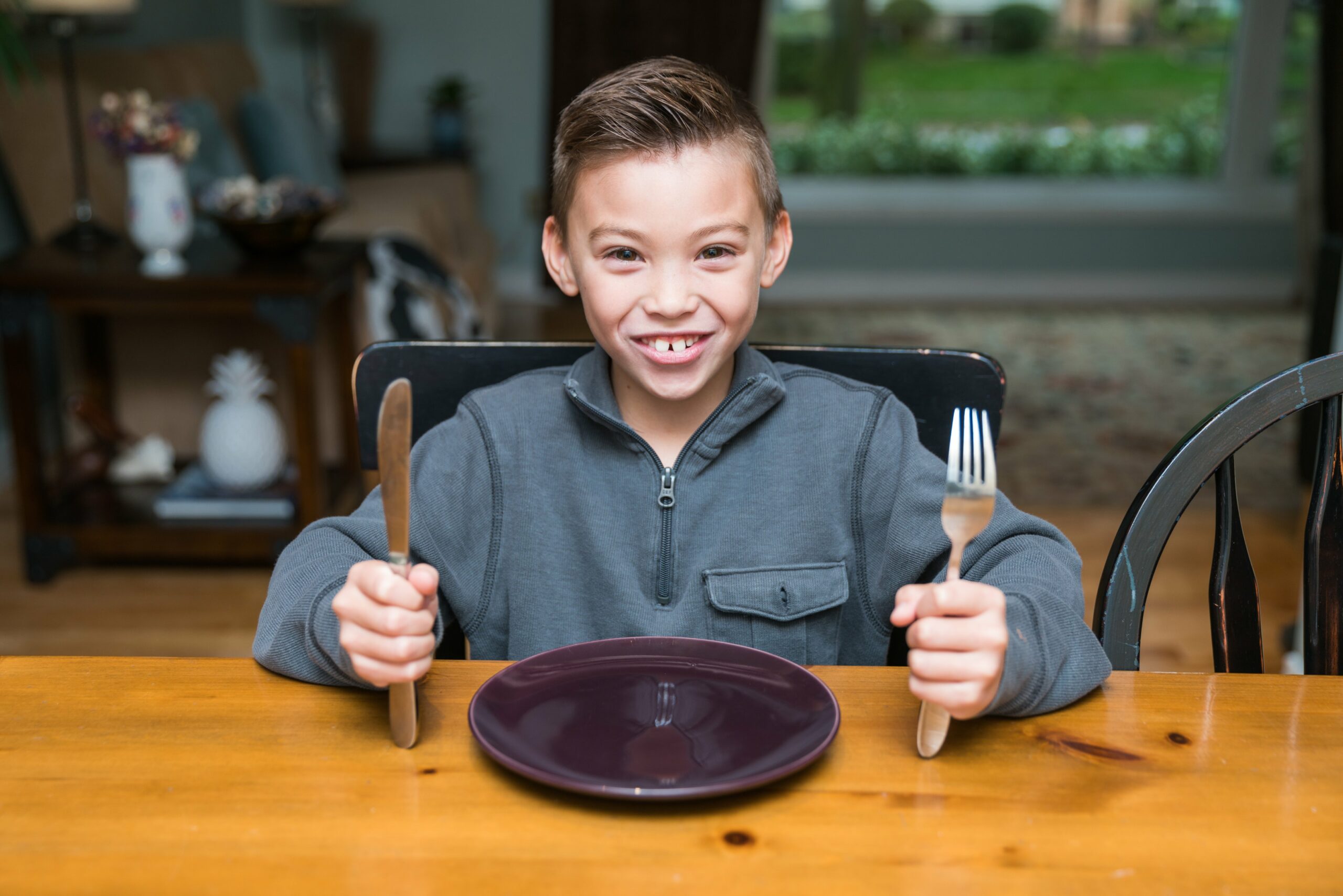 picture of kid holding cutlery in front of plate